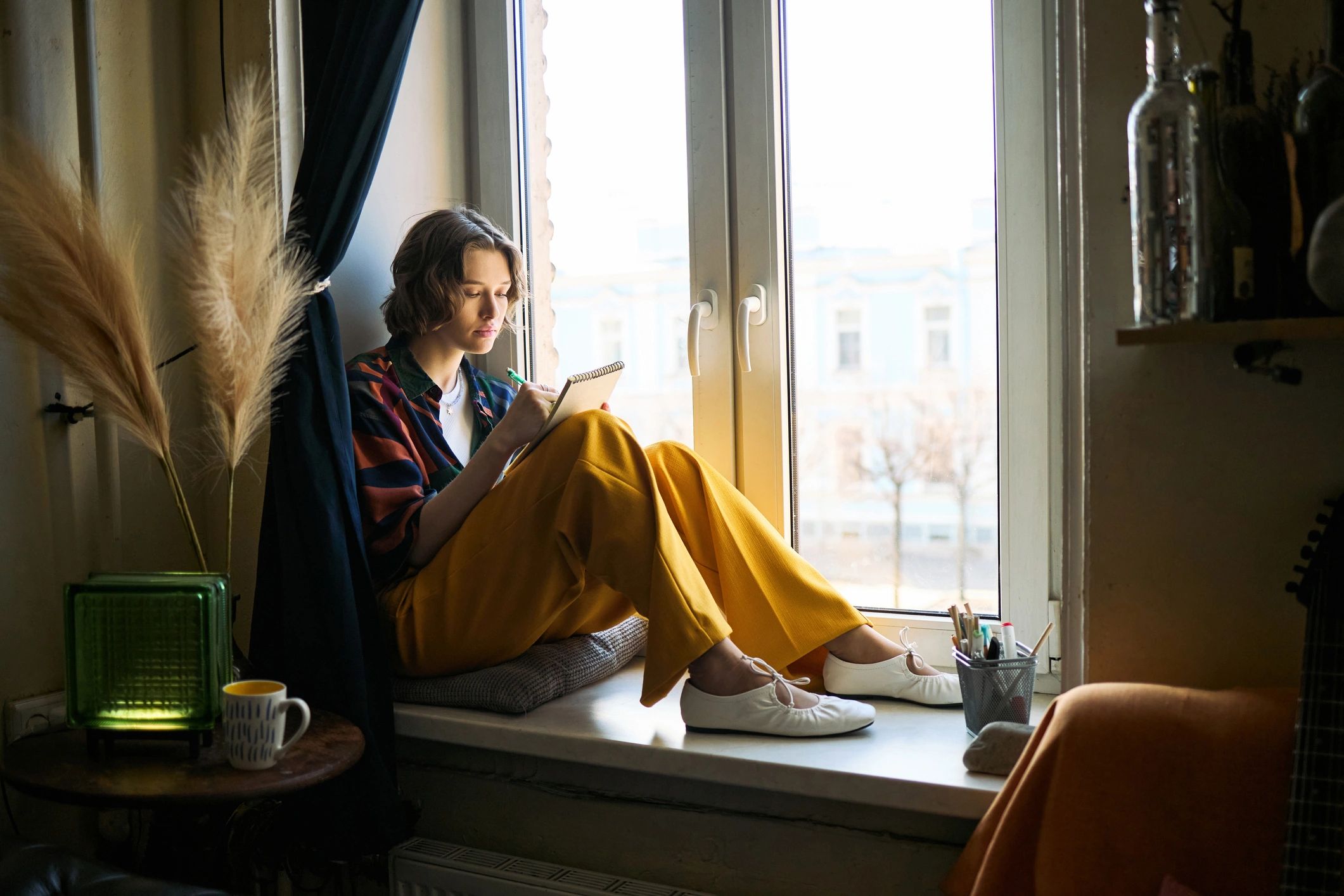 Woman journaling by a window to represent reflection and intentional growth